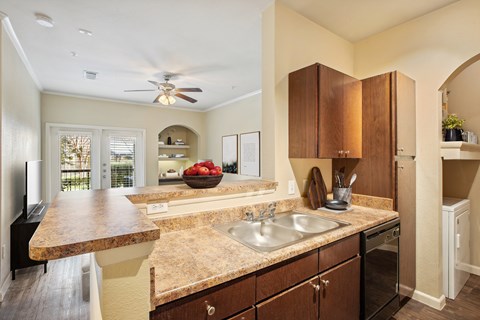 A kitchen with a marble countertop and wooden cabinets.